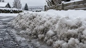Tung, våt brøytekant ved enden av en snødekt oppkjørsel.